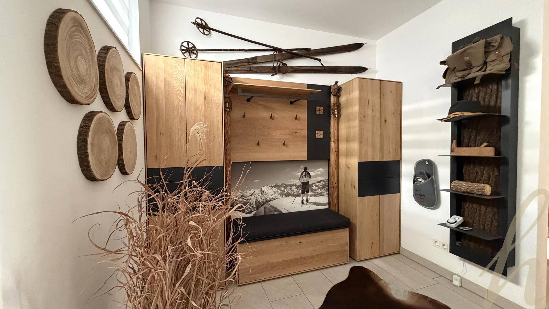 Detailansicht des Eingangsbereichs mit Holzeinbauten, Sitzgelegenheit und alpiner Dekoration.