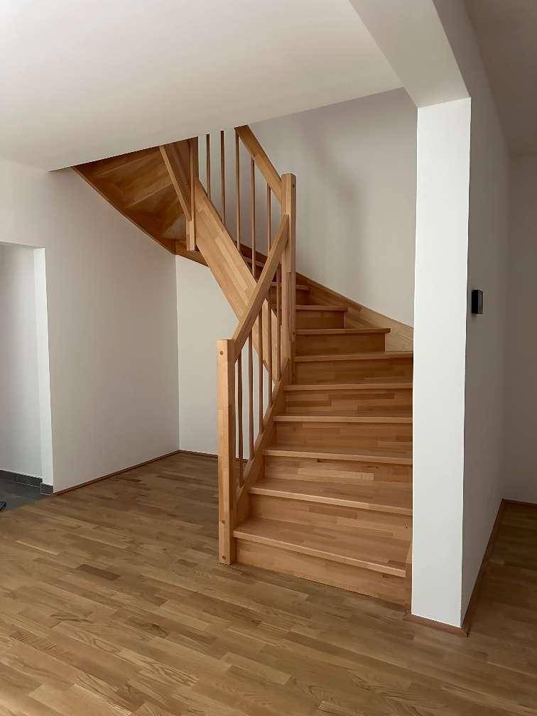 Heller Eingangsbereich mit Holztreppe, die in die oberen Stockwerke führt.