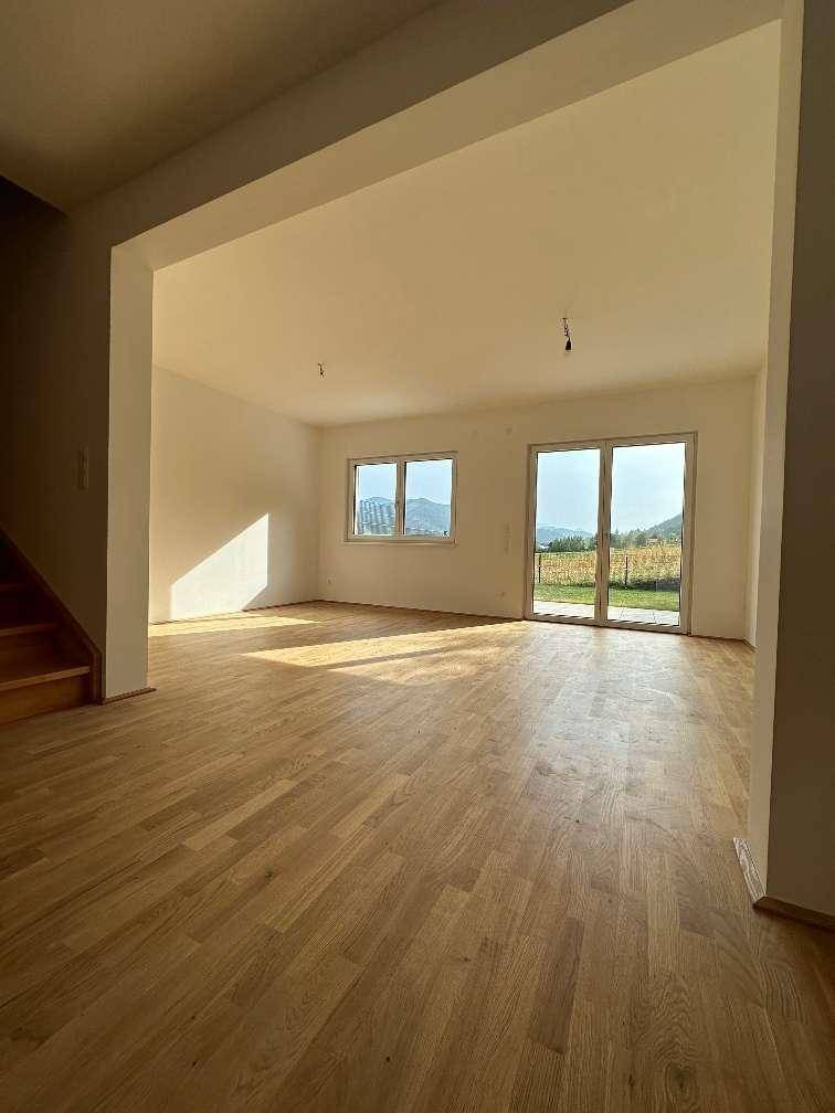 Helles Wohnzimmer mit Holzboden und Zugang zur Terrasse mit Blick ins Grüne.
