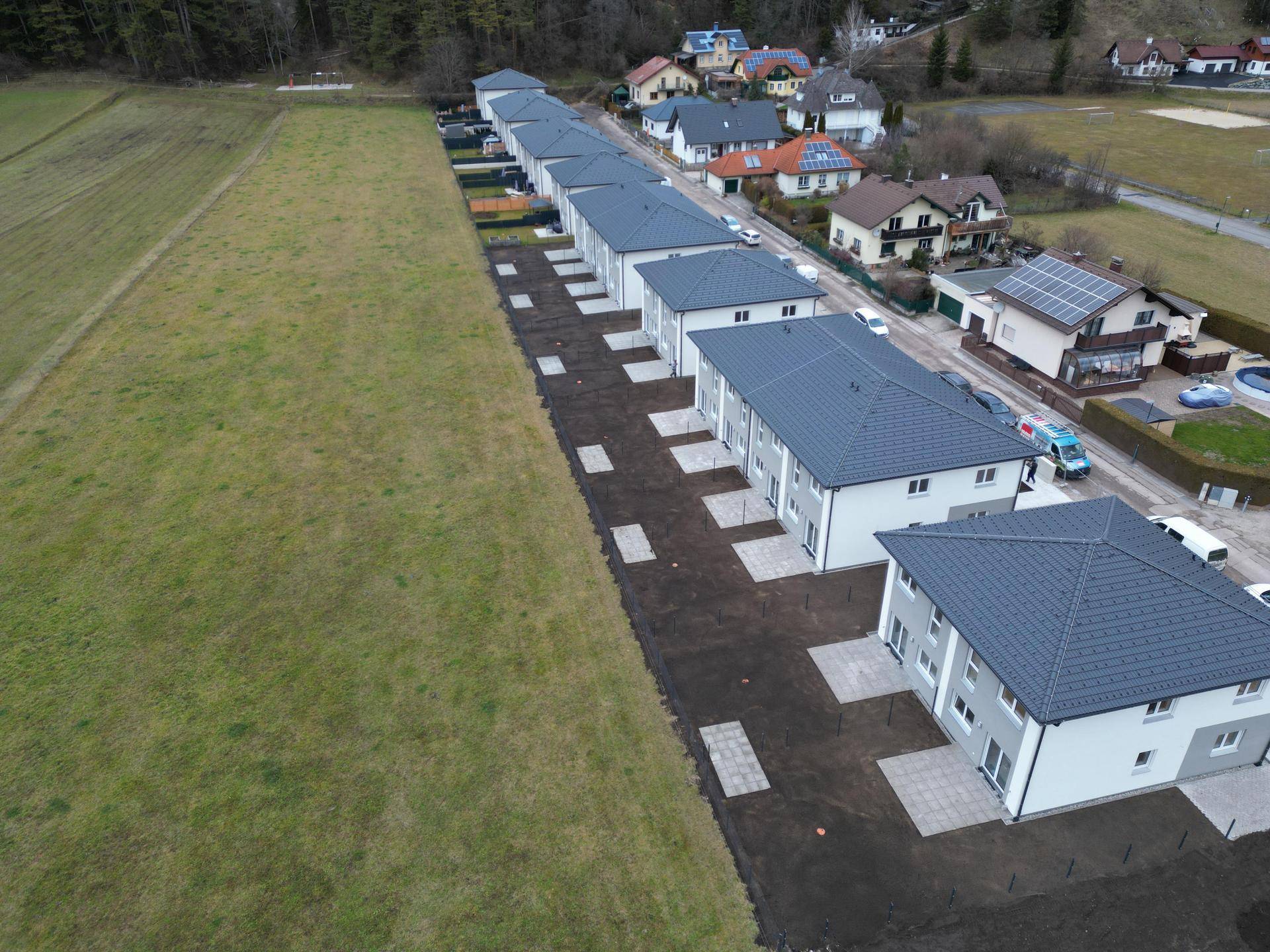 Überblick über eine Reihe von Neubauhäusern mit Gärten und angrenzendem Feld.