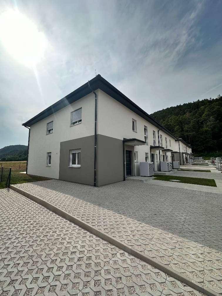 Vorderansicht der modernen Reihenhäuser mit gepflasterten Parkplätzen und klarem Himmel.