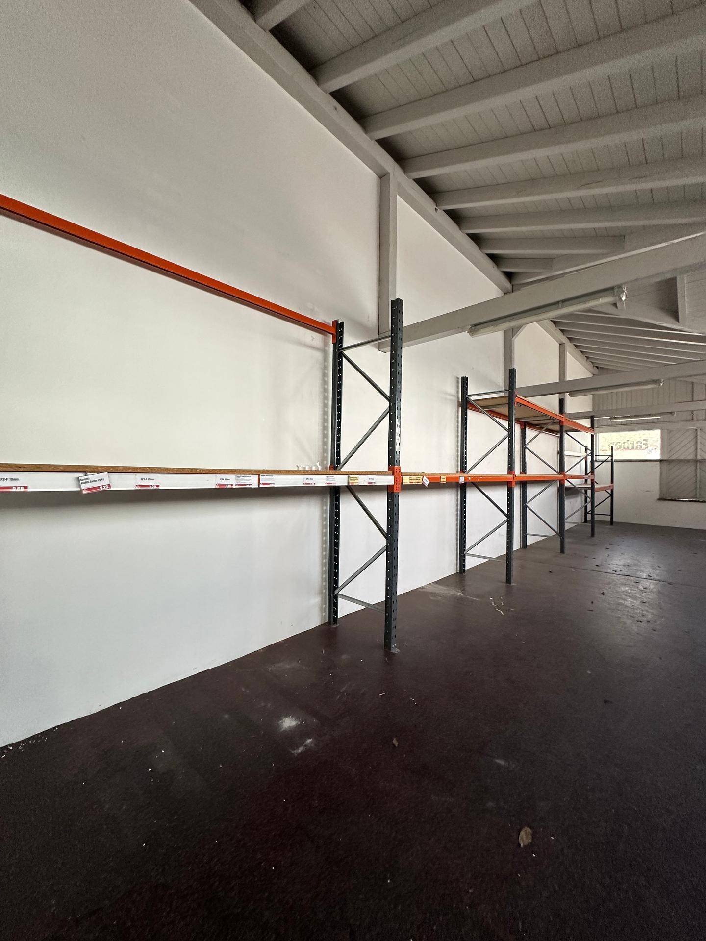 Lagerhalle mit hohen Regalen und einem robusten Holzboden, ideal für gewerbliche Nutzung.