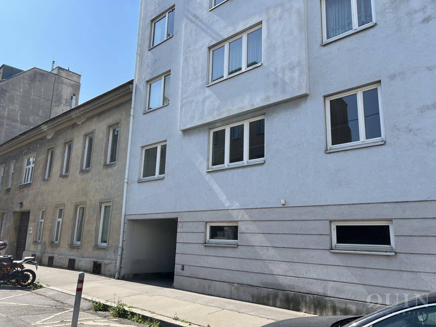 Mehrstöckiges Wohngebäude mit schlichter Fassade und vielen Fenstern an einem sonnigen Tag.