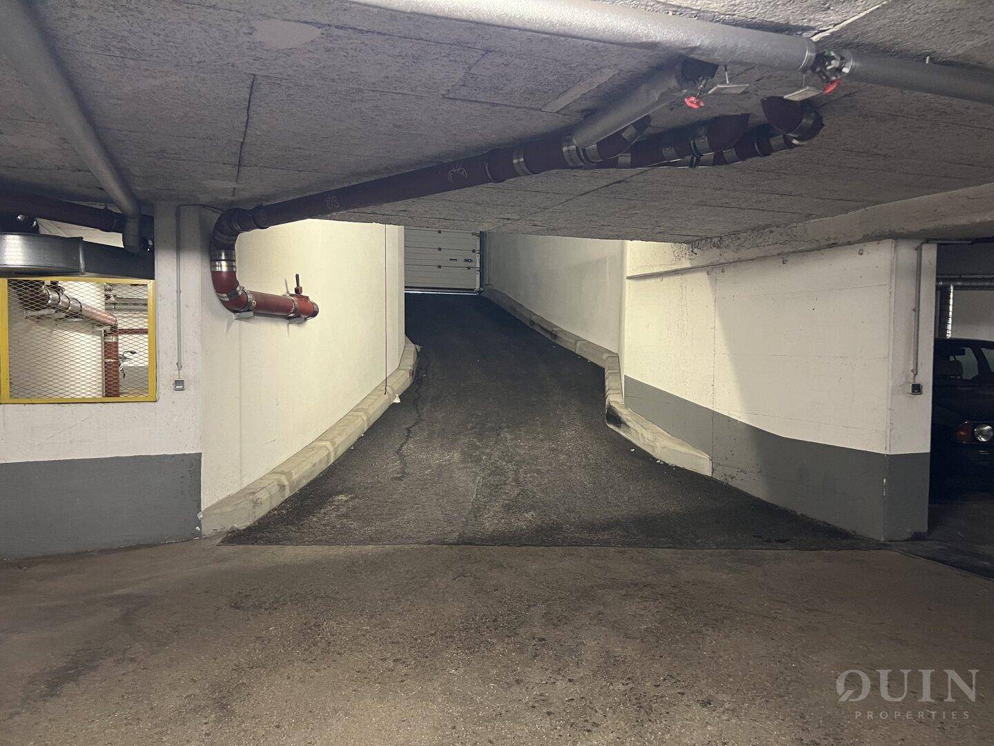 Zufahrtsrampe zur Tiefgarage mit sichtbaren Leitungen an der Decke.