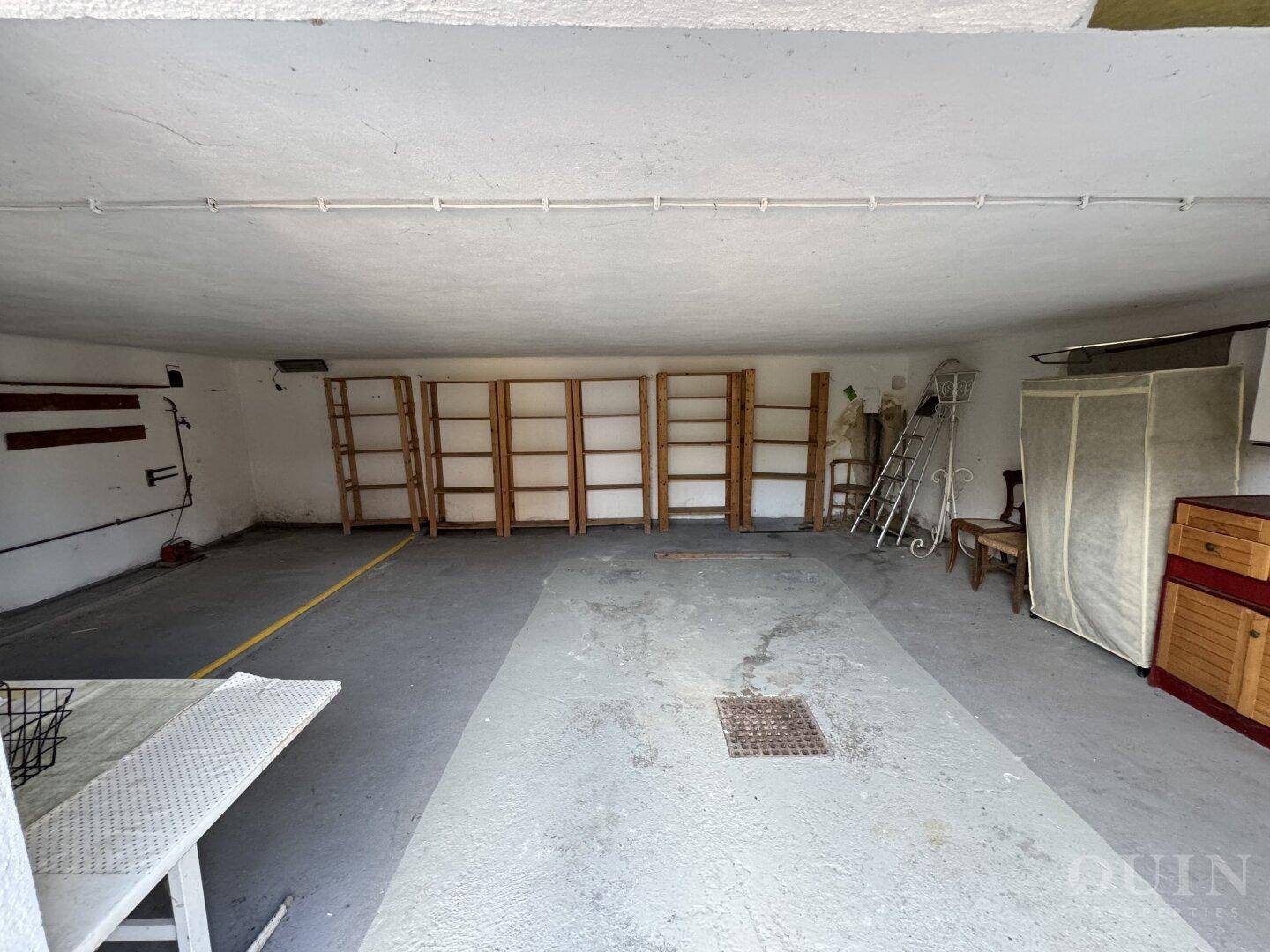 Geräumige Garage mit Betonboden und Regalen für Lagerzwecke.