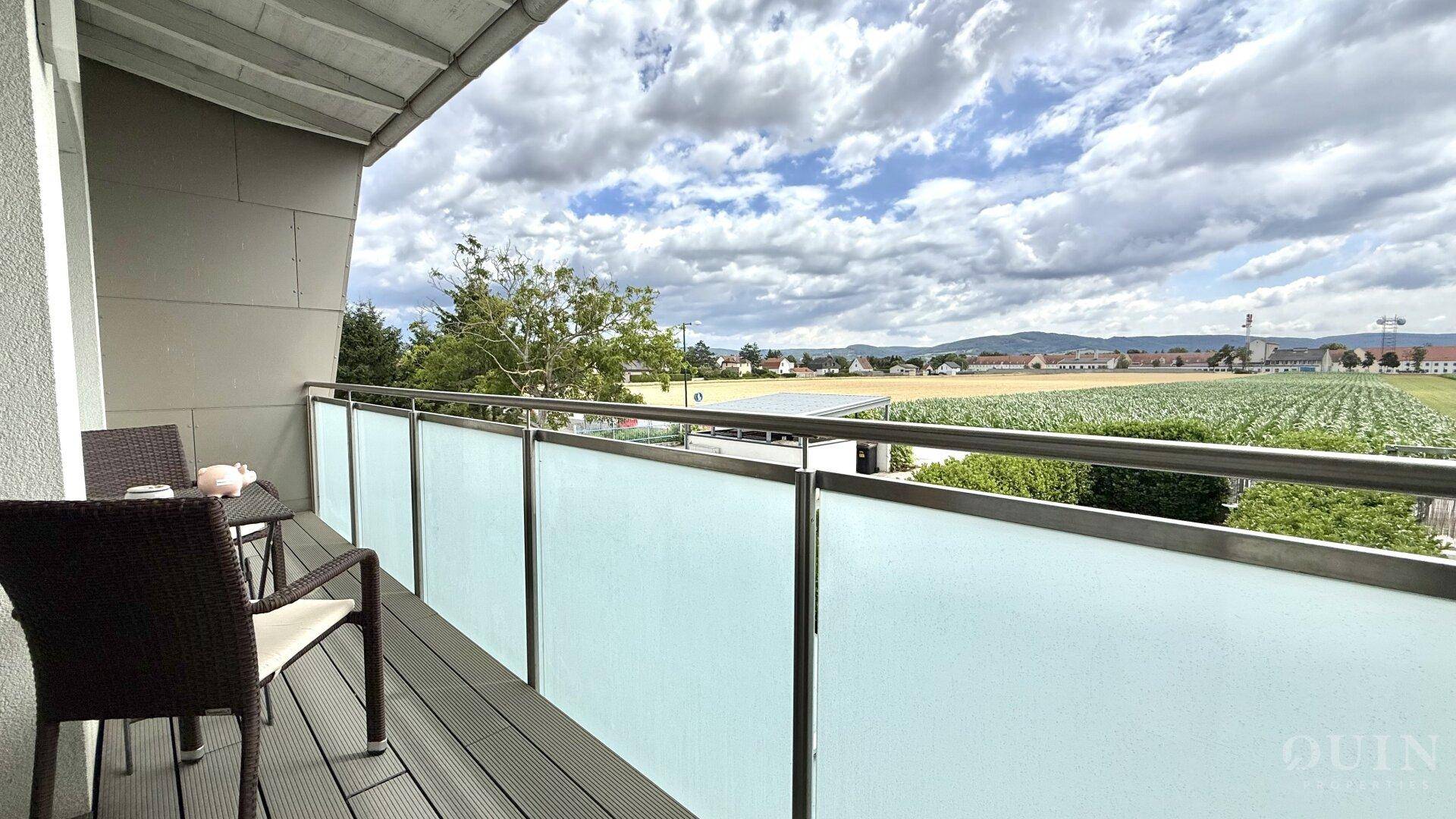 Balkon mit Sitzgelegenheiten und weitem Blick über Felder und die umliegende Landschaft.