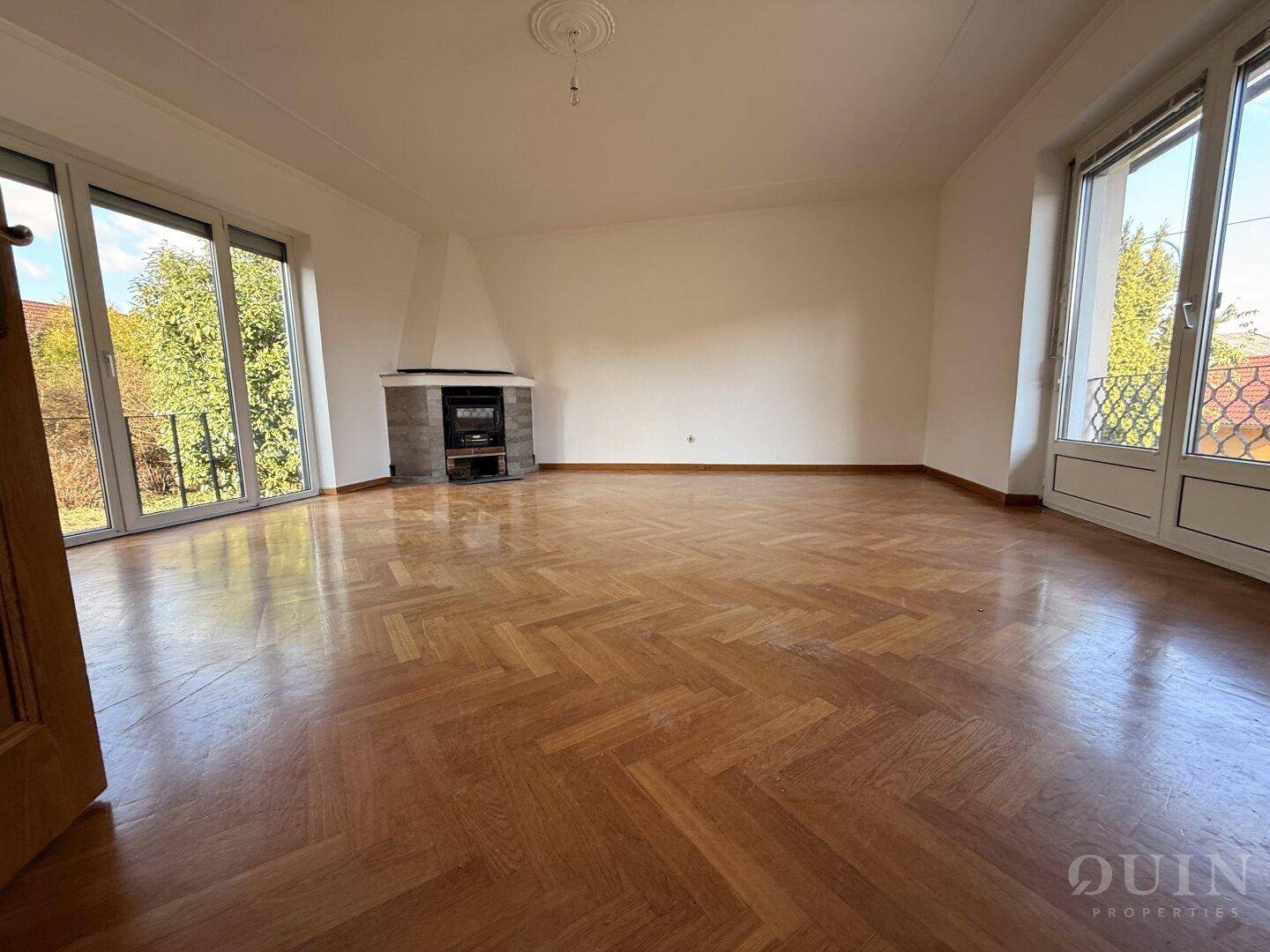 Helles Wohnzimmer mit Fischgrätparkett, Kamin und Zugang zu einem französischen Balkon.