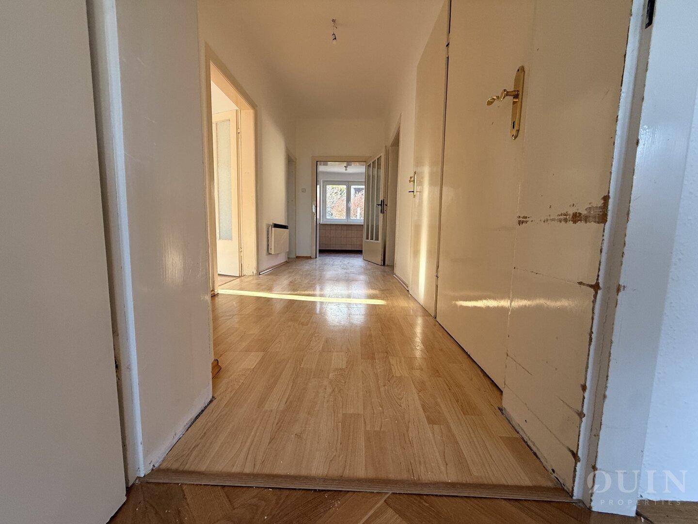 Langer Flur mit Holzboden, der verschiedene Zimmer miteinander verbindet.