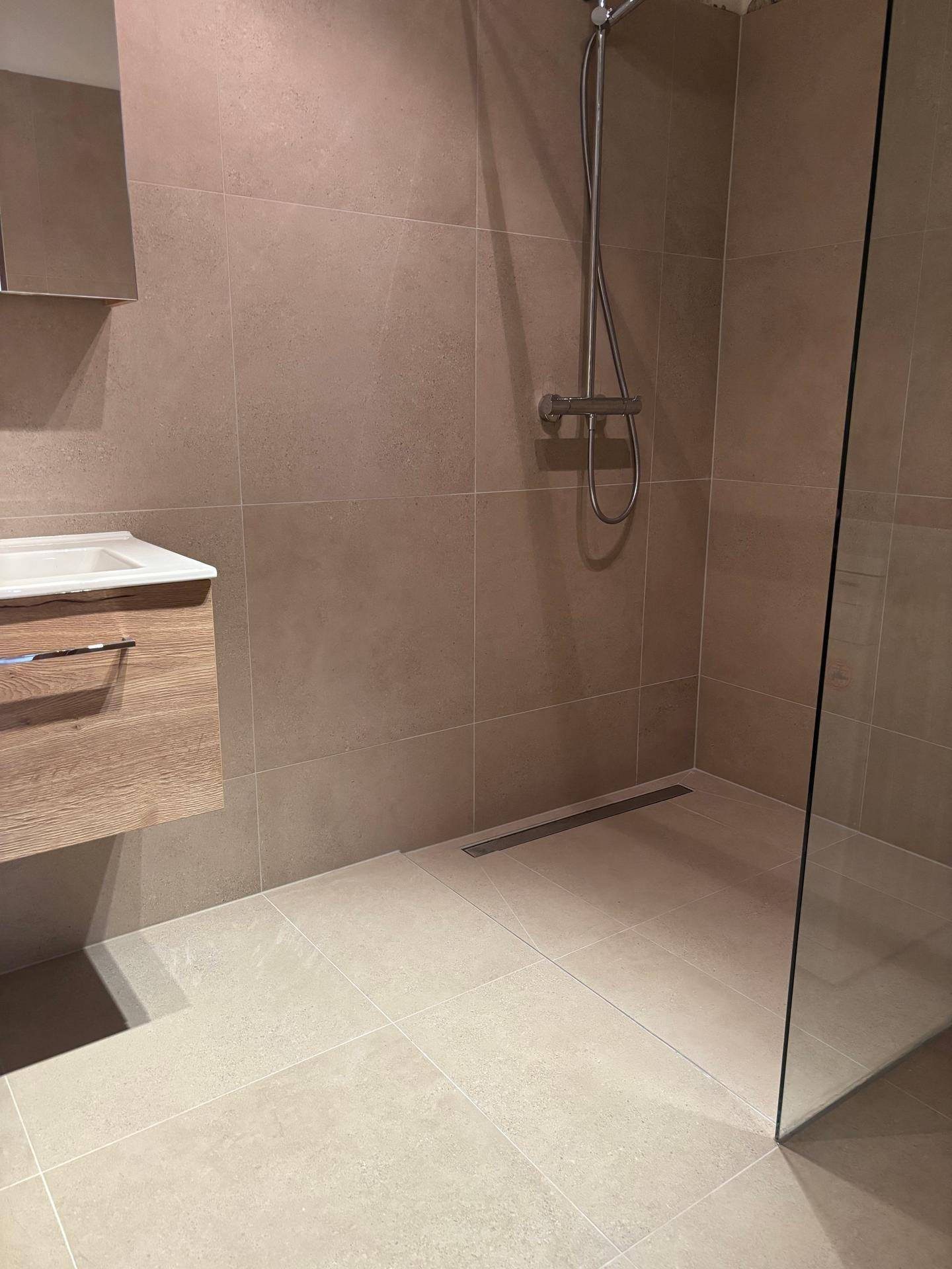 Begehbare Dusche mit Glasabtrennung und modernen Fliesen im Badezimmer.