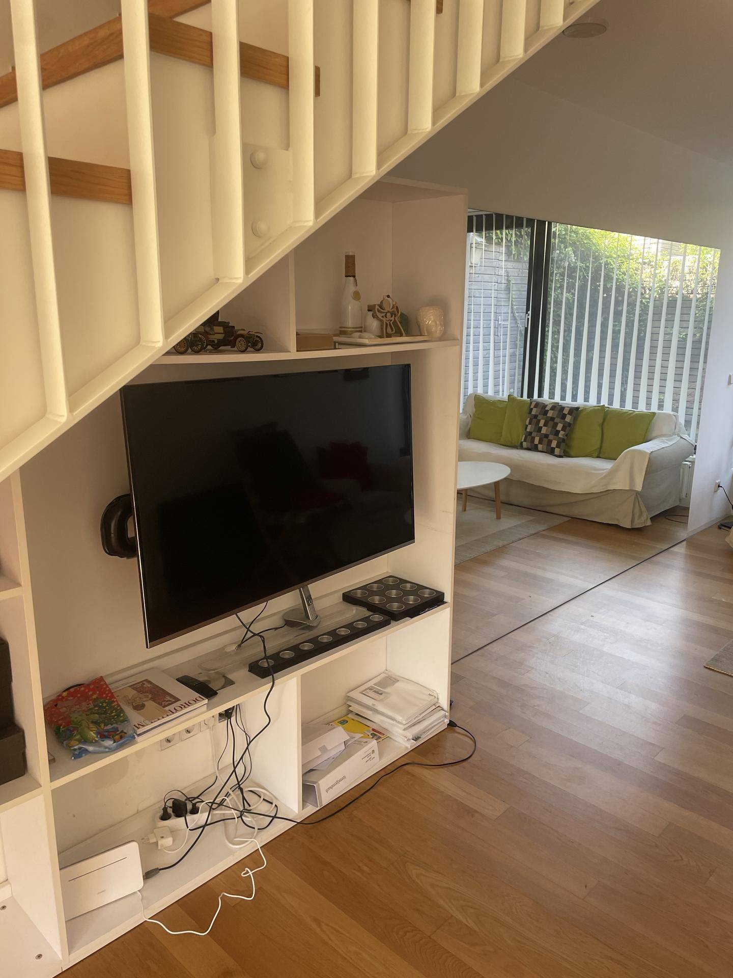 Gemütlicher Wohnbereich unter der Treppe mit Fernseher und Blick auf den Garten.