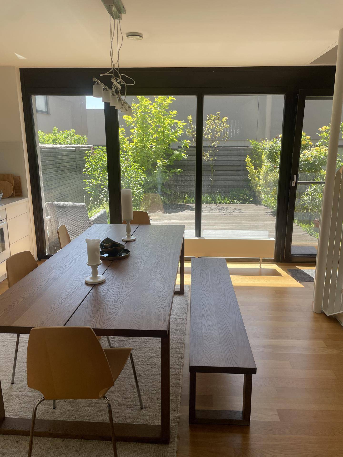 Geräumiger Essbereich mit Holztisch und Bank, großen Fenstern und Zugang zur Terrasse.