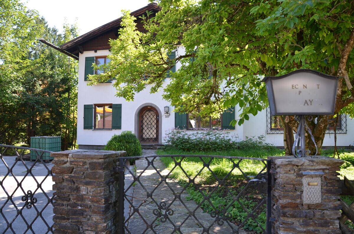 Charmantes Haus mit weißer Fassade, grünen Fensterläden und einem dekorativen Eingangsbereich.