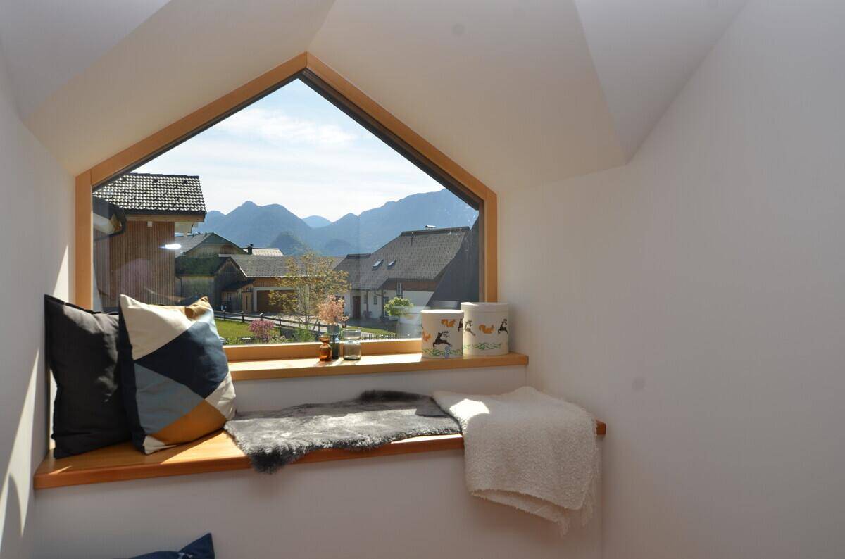 Gemütliche Fensternische mit dreieckigem Fenster und atemberaubendem Blick auf die umliegende Berglandschaft.