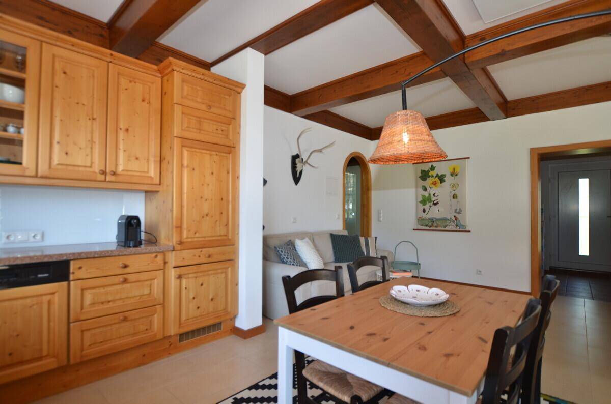 Rustikale Holzküche mit Einbauschränken und angrenzendem Essbereich mit Holztisch.
