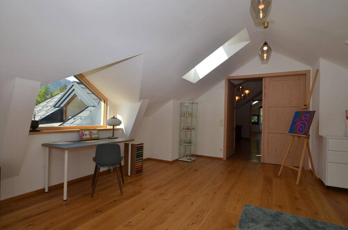 Funktionaler Arbeitsbereich im Dachgeschoss mit Schreibtisch, Holzboden und Dachfenster.