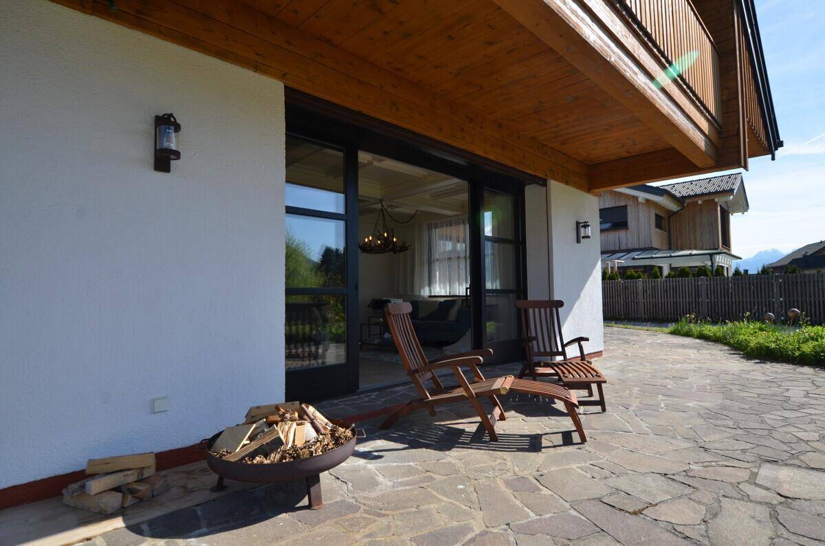 Großzügige Steinterrasse mit bequemen Holzliegen und Feuerstelle, direkt am Haus gelegen.