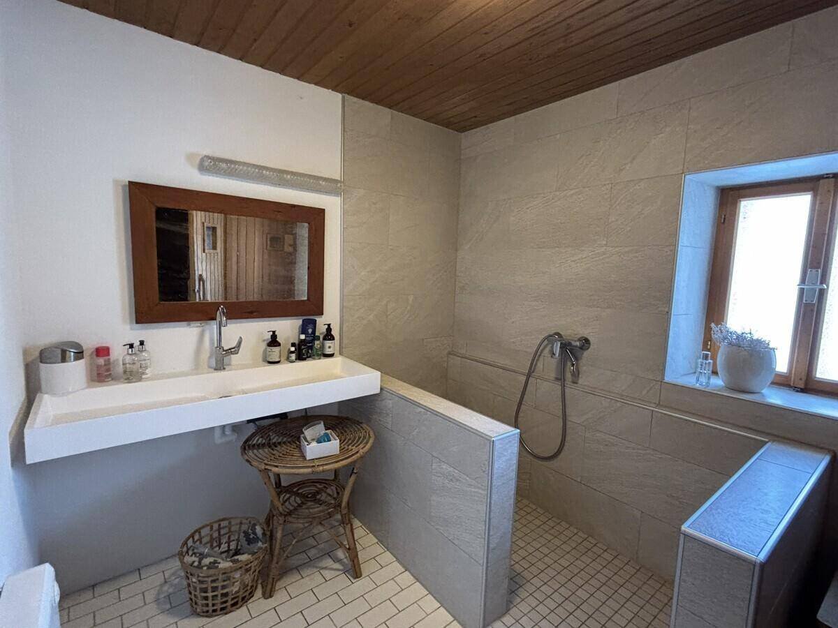 Modernisiertes Badezimmer mit Fliesen, Holzdecke und einem Fenster.