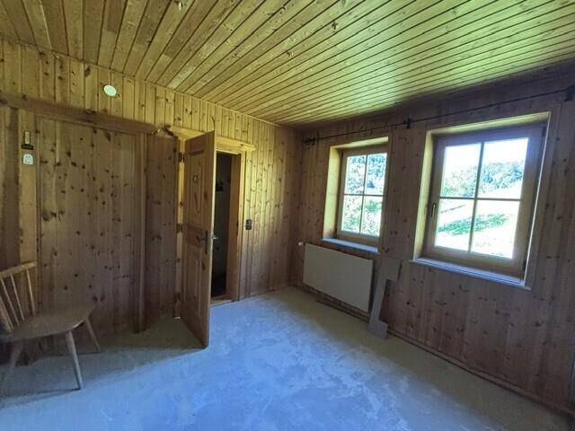 Helles Zimmer mit Holzvertäfelung und zwei Fenstern, ideal als Schlaf- oder Arbeitszimmer.