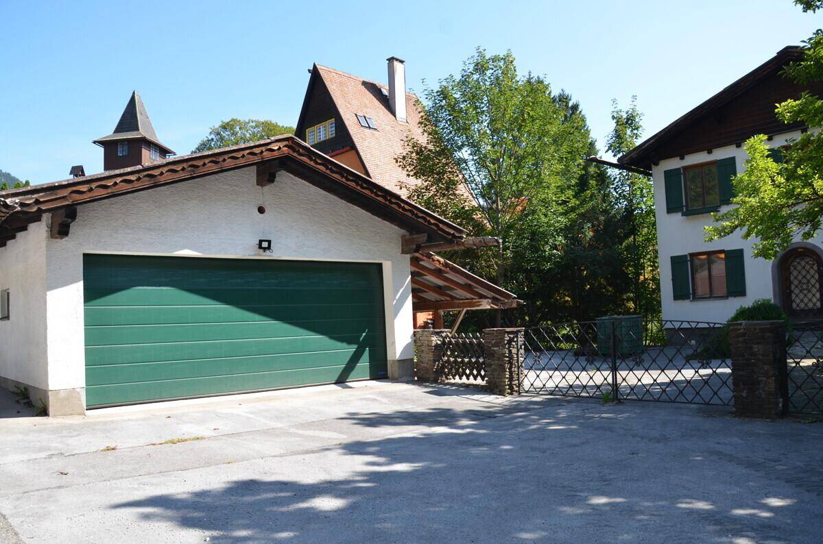 Separate Garage mit grünem Tor und zusätzlichem überdachtem Stellplatz.