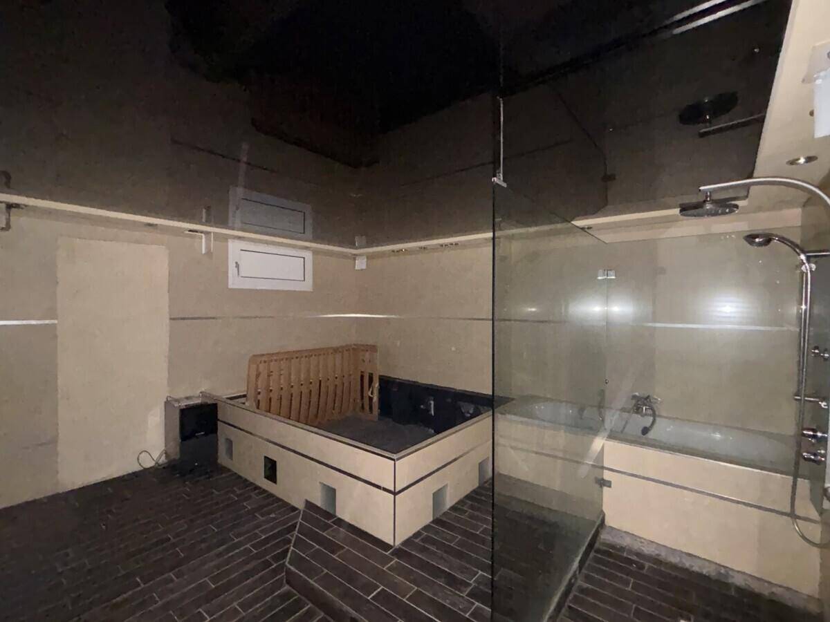 Badezimmer mit Badewanne und Whirlpool, dunklem Boden und moderner Glasabtrennung.