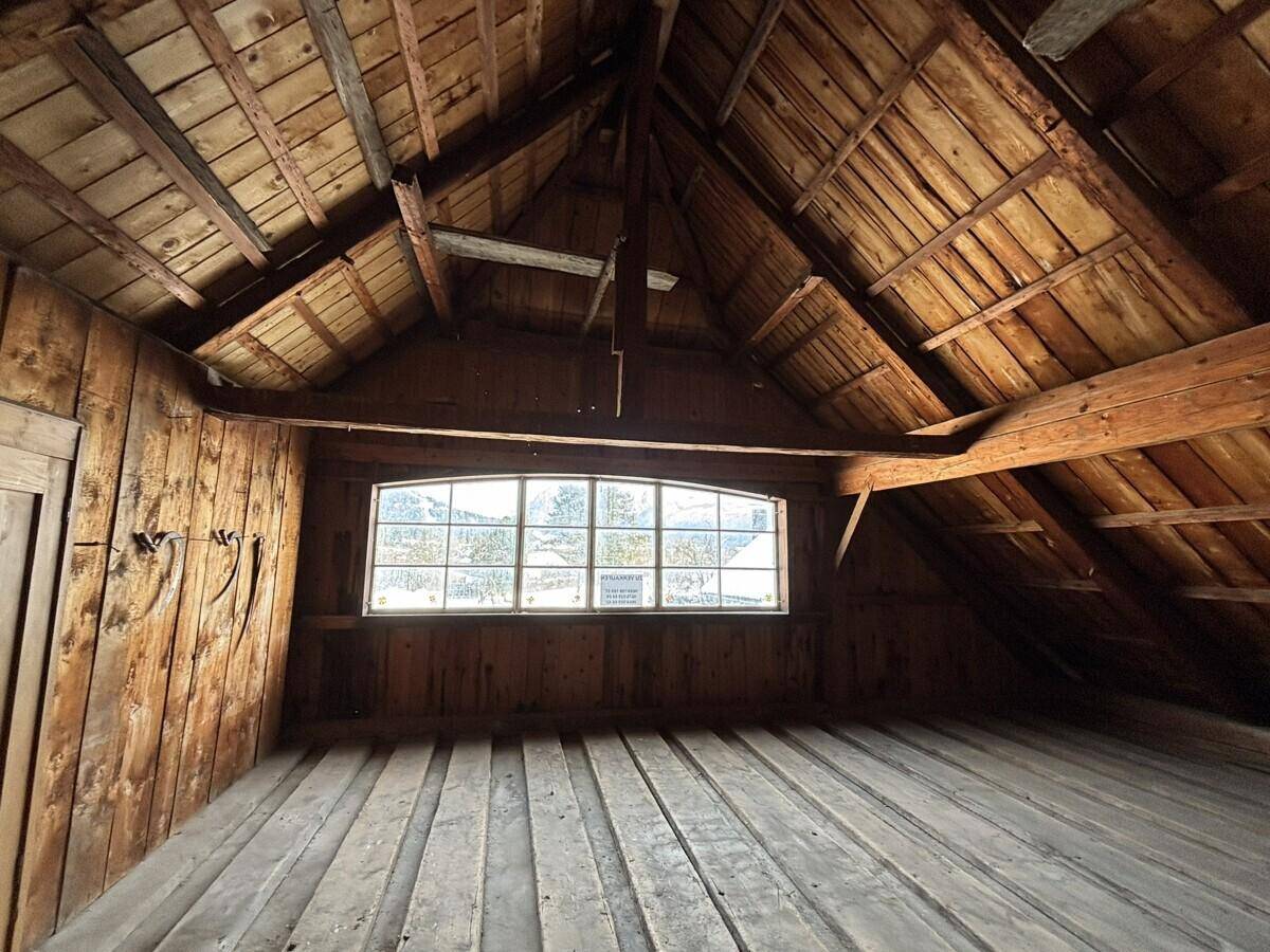 Geräumiger Dachboden mit sichtbarer Holzkonstruktion und einem Fenster.