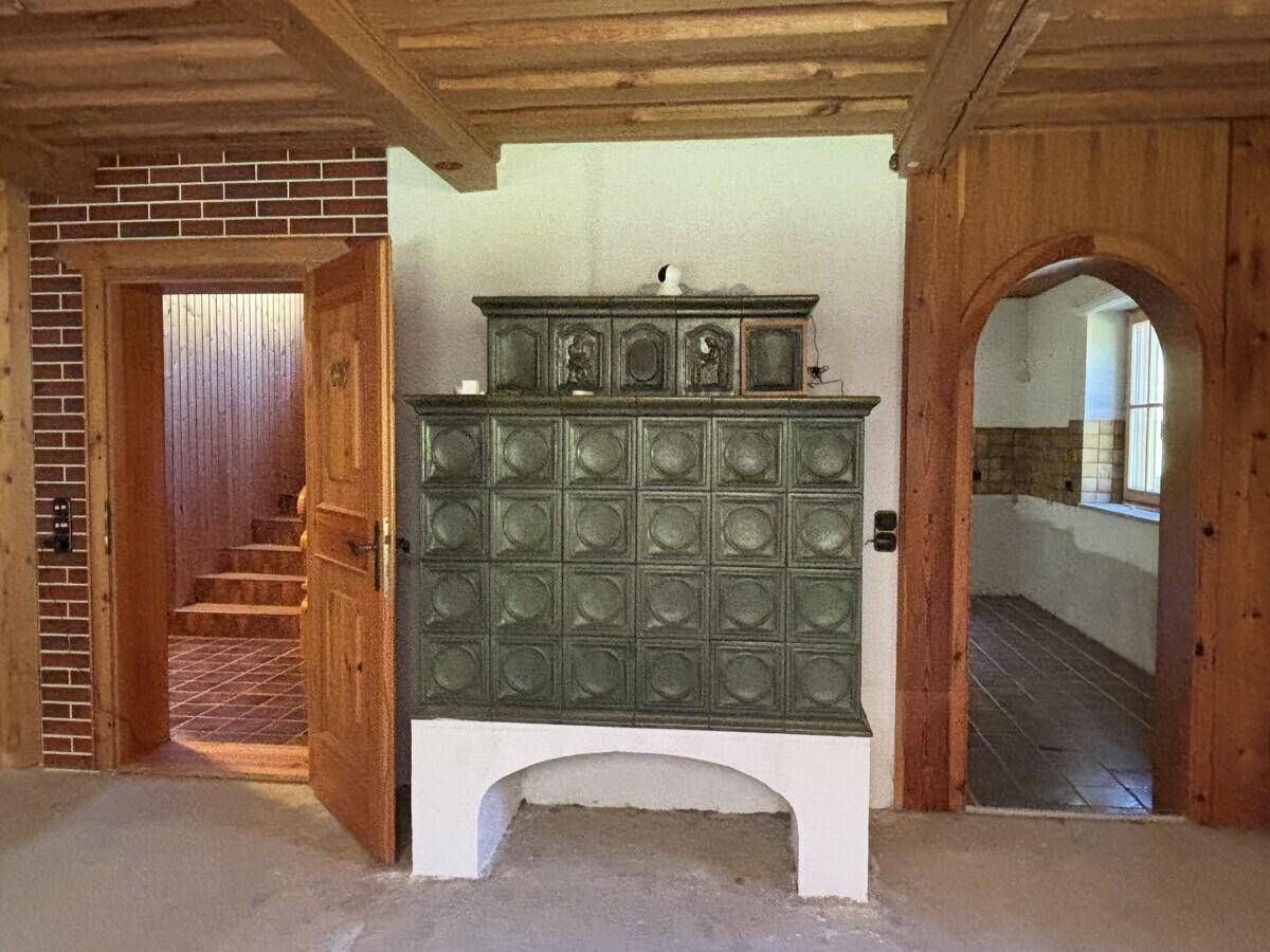 Detailansicht eines traditionellen Kachelofens in einem Raum mit Holzelementen und Ziegelwand.