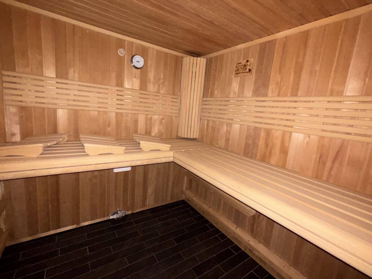 Geräumige Holzsauna mit mehreren Bänken und dunklem Fliesenboden für Entspannung.