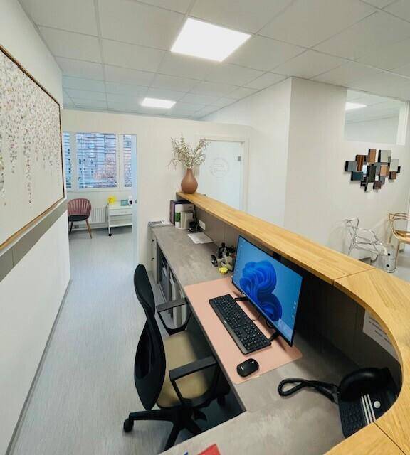 Moderner Empfangstresen aus Holz mit Computerarbeitsplatz und stilvoller Dekoration.