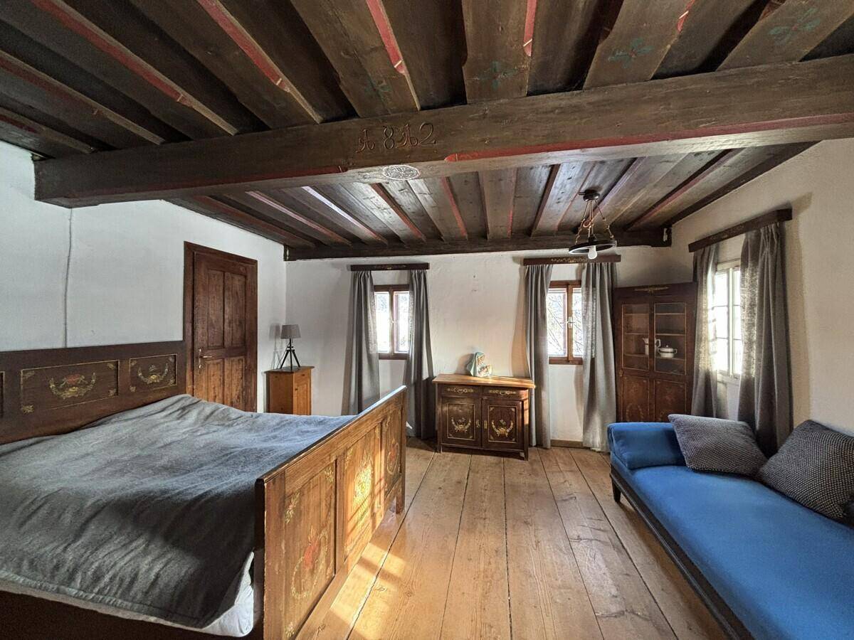 Geräumiges Schlafzimmer mit Doppelbett, Holzboden, sichtbaren Balken und traditionellen Möbeln.