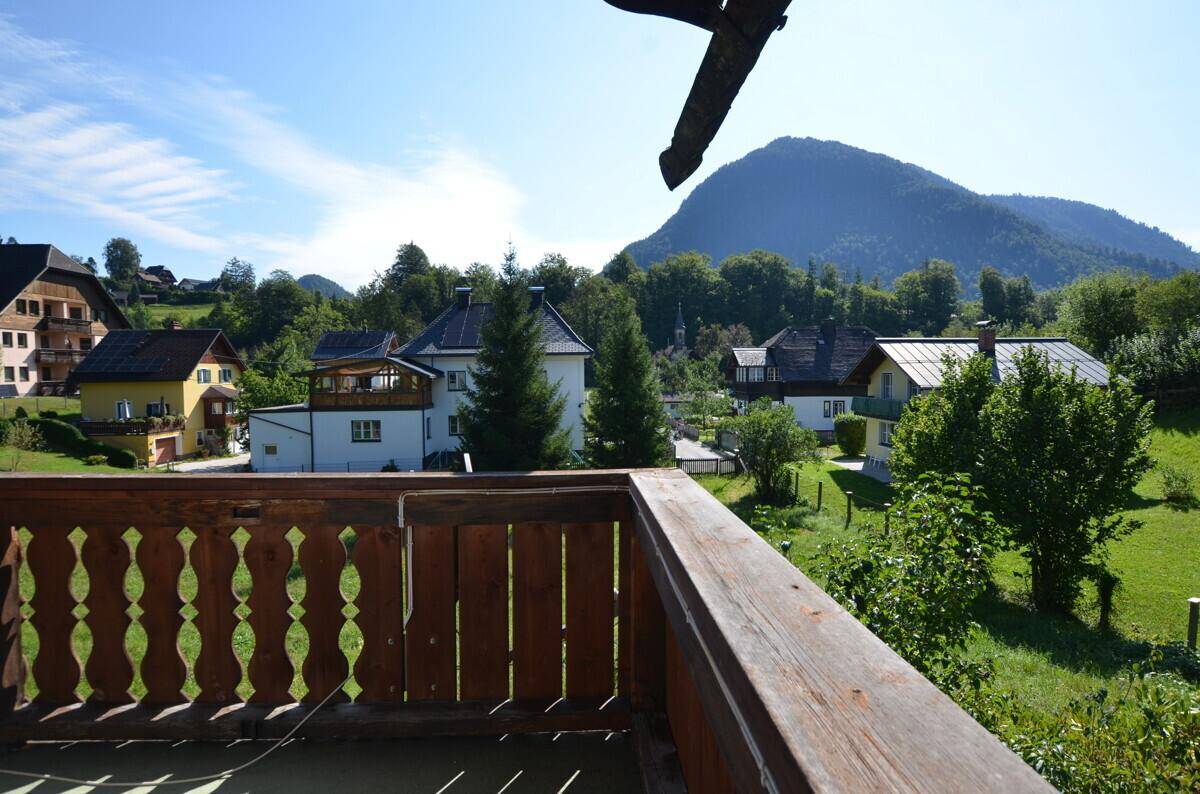 Balkon mit Holzgeländer und Panoramablick auf die Berge und die grüne Landschaft.