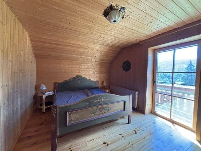 Gemütliches Schlafzimmer mit Holzwänden, Holzboden und Zugang zu einem Balkon mit Bergblick.