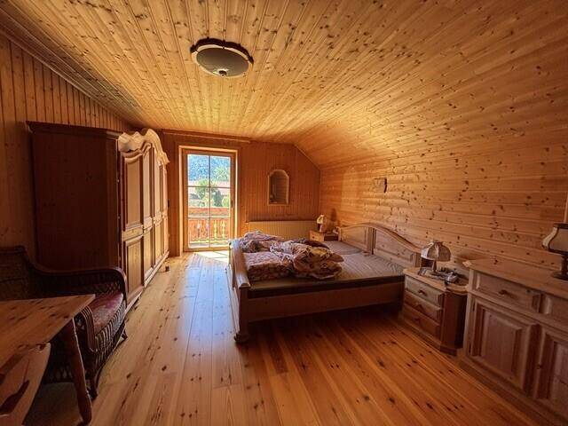 Schlafzimmer im Landhausstil mit Holzboden, Holzvertäfelung und Balkonzugang.