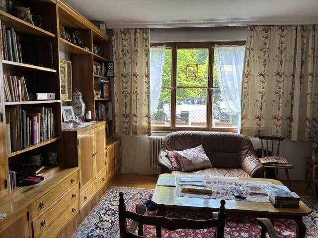 Gemütliches Wohnzimmer mit Bücherregal, Sofa und Blick ins Grüne.