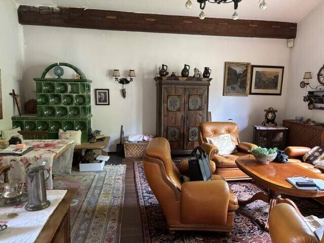 Traditionell eingerichtetes Wohnzimmer mit Kachelofen, Ledersesseln und Holzelementen.