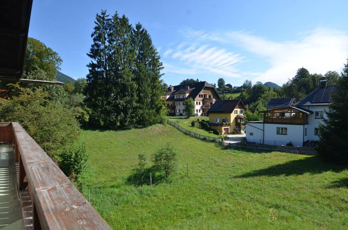 Weitläufiger Blick über grüne Wiesen und umliegende Häuser in sonniger Umgebung.