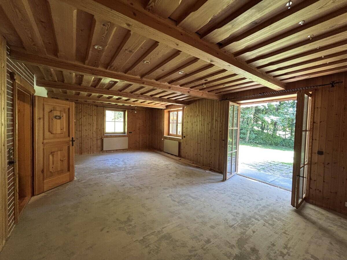 Heller Wohnraum mit Holzbalkendecke, Holzwänden und Zugang zum Außenbereich.