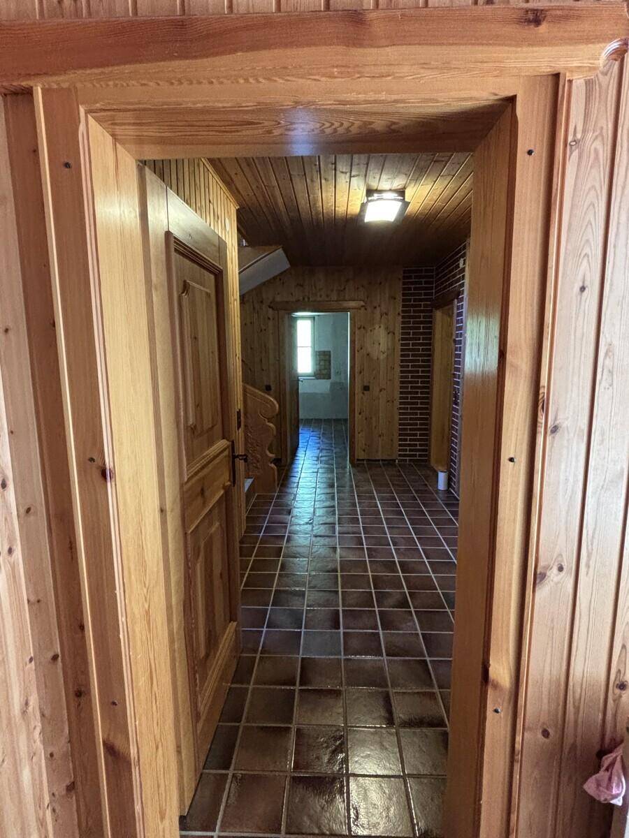Gemütlicher Flur mit Holzvertäfelung an Wänden und Decke sowie rustikalen Fliesen.