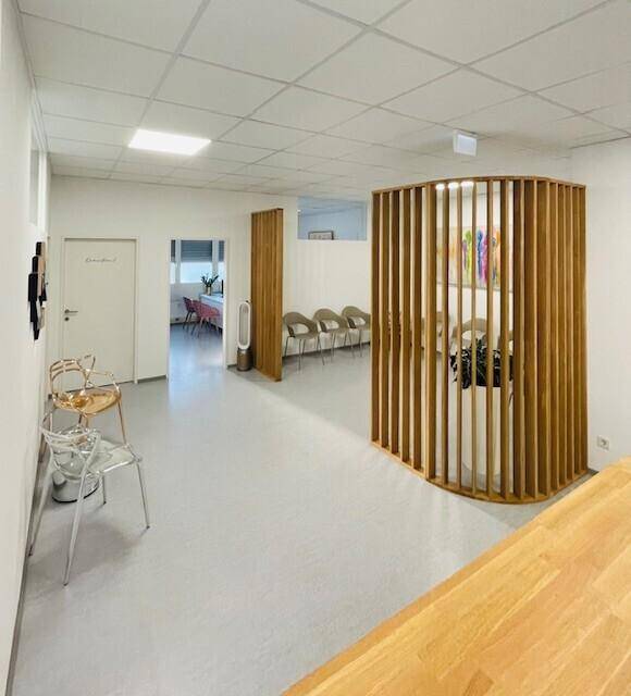 Geräumiger Wartebereich mit modernen Holzlamellen-Trennwänden und bequemen Sitzgelegenheiten.