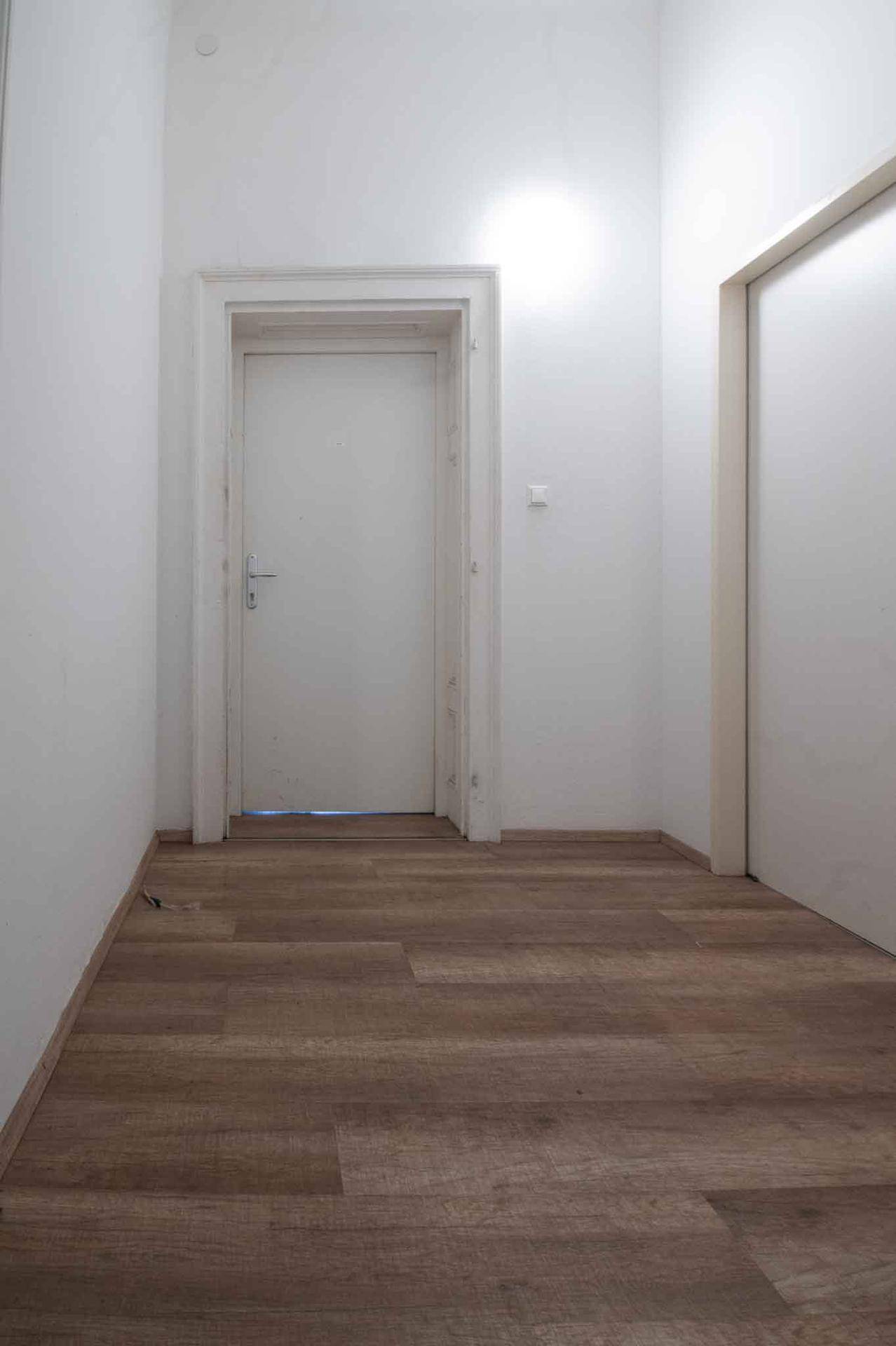 Heller Flur mit neuem Laminatboden und weißen Türen, die zu verschiedenen Räumen führen.