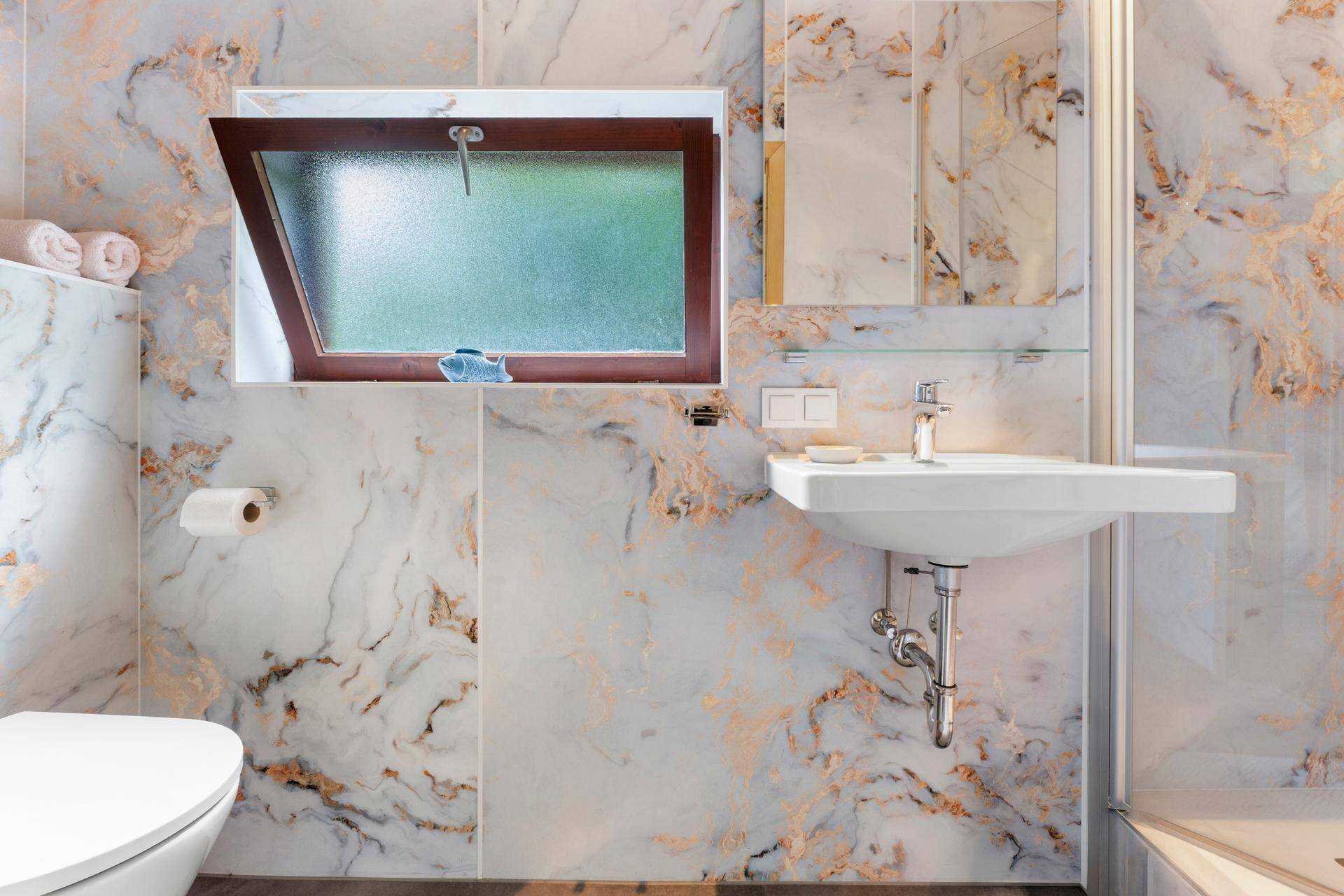 Elegantes Badezimmer mit Dusche, WC und Waschbecken, verziert mit Marmor-Effekt-Fliesen.