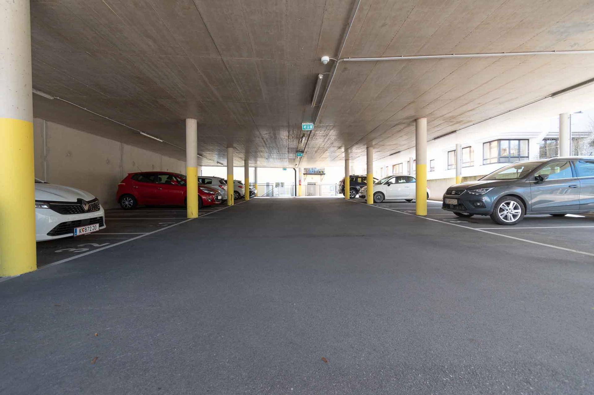 Geräumige Tiefgarage mit vielen Parkplätzen und gelb gestrichenen Säulen.