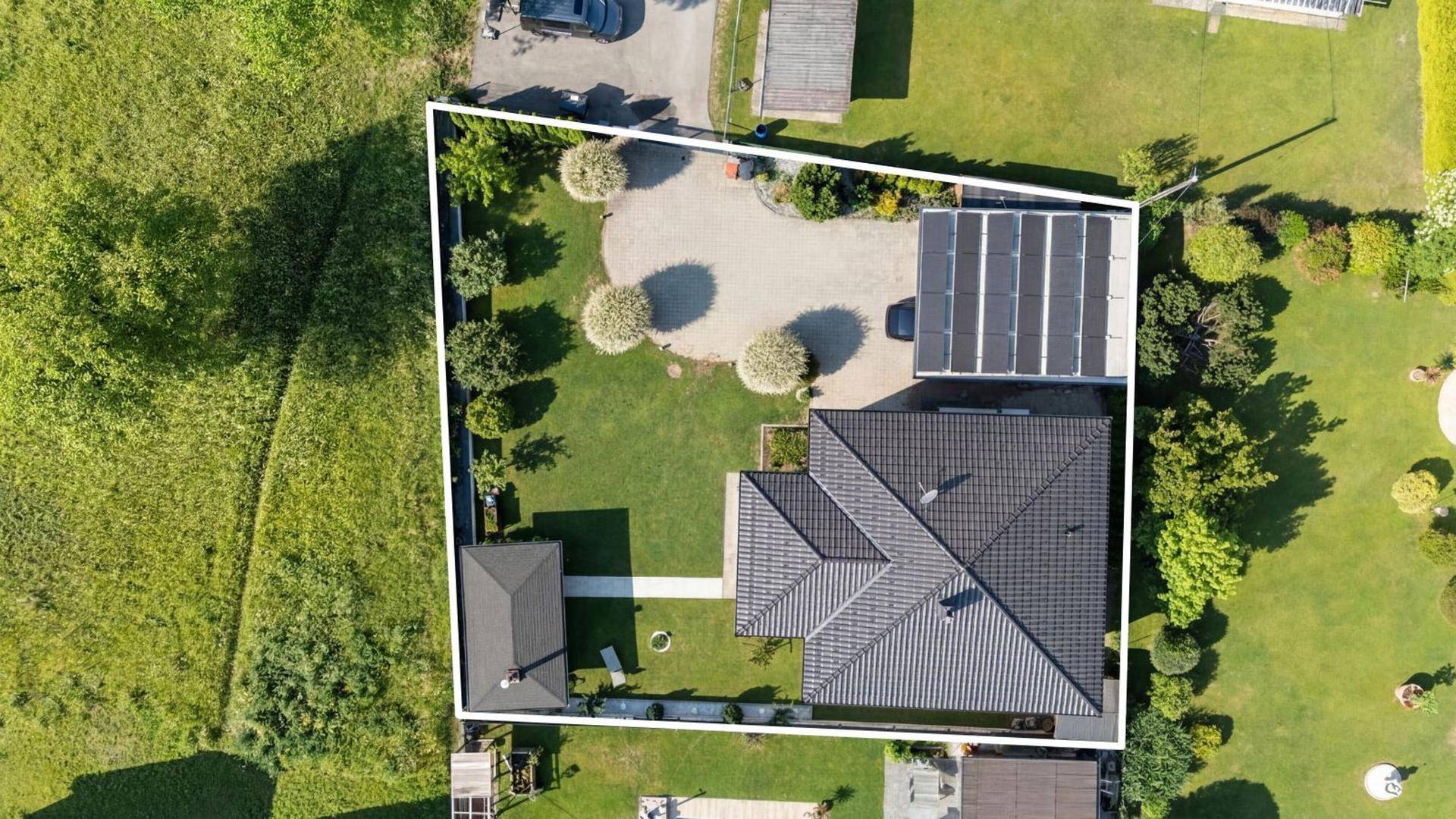 Draufsicht des Grundstücks mit Haus, Garten, Auffahrt und Carport mit Solaranlage.