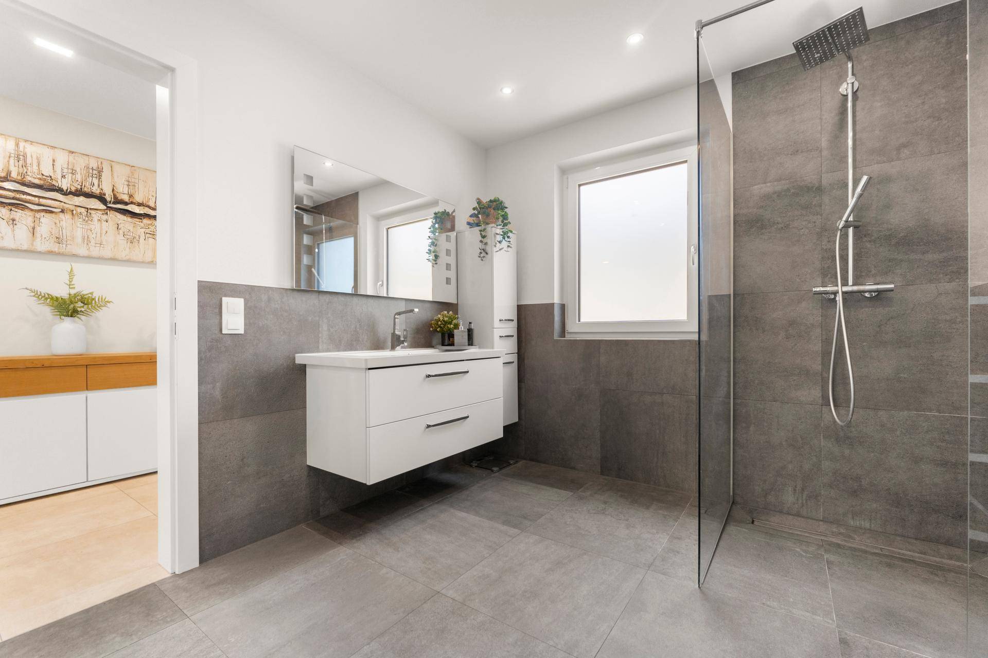 Geräumiges Badezimmer mit modernem Waschtisch, großem Spiegel und begehbarer Dusche.
