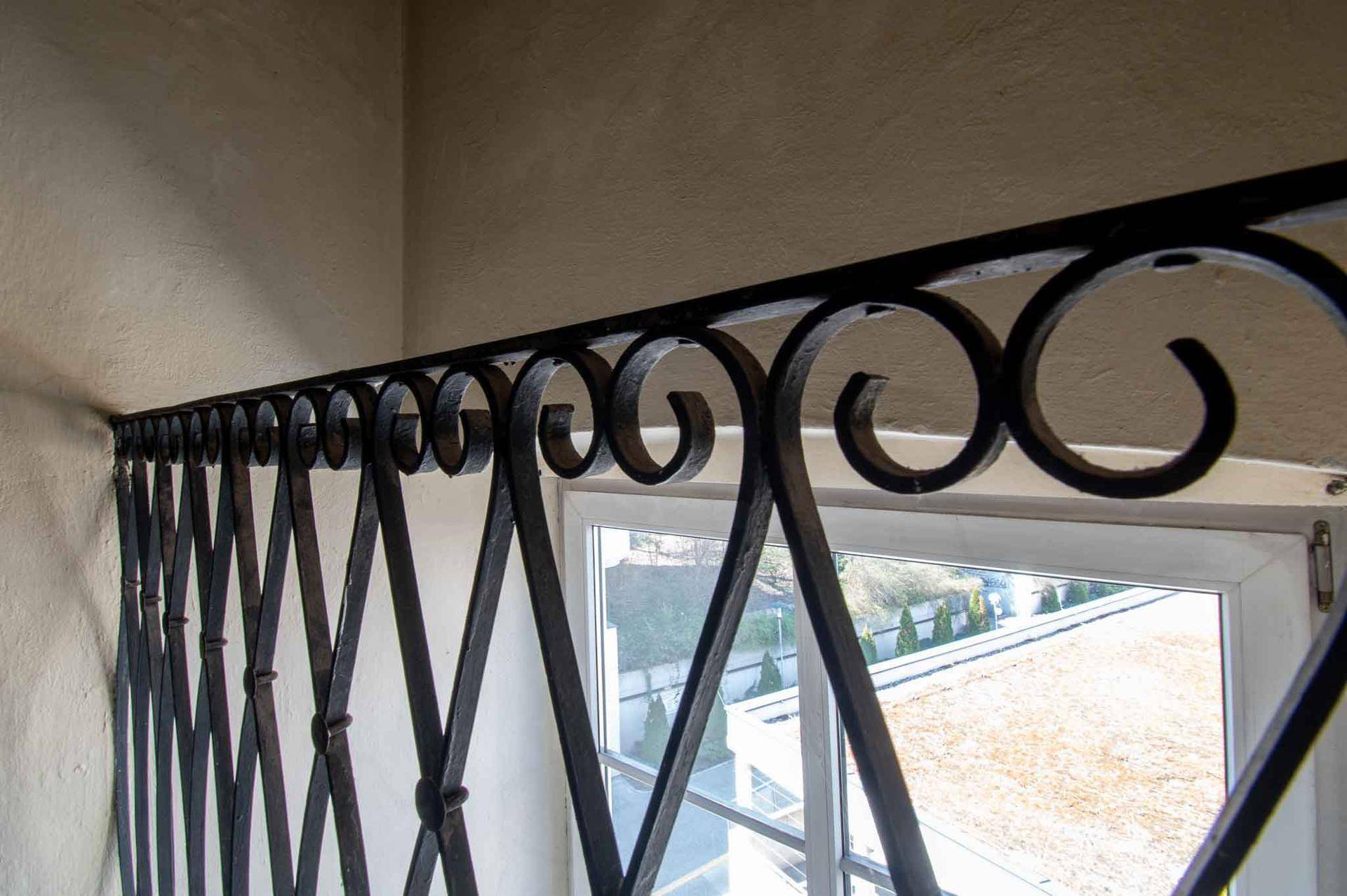 Fenster mit kunstvollem schmiedeeisernem Gitter, das einen Blick nach draußen bietet.