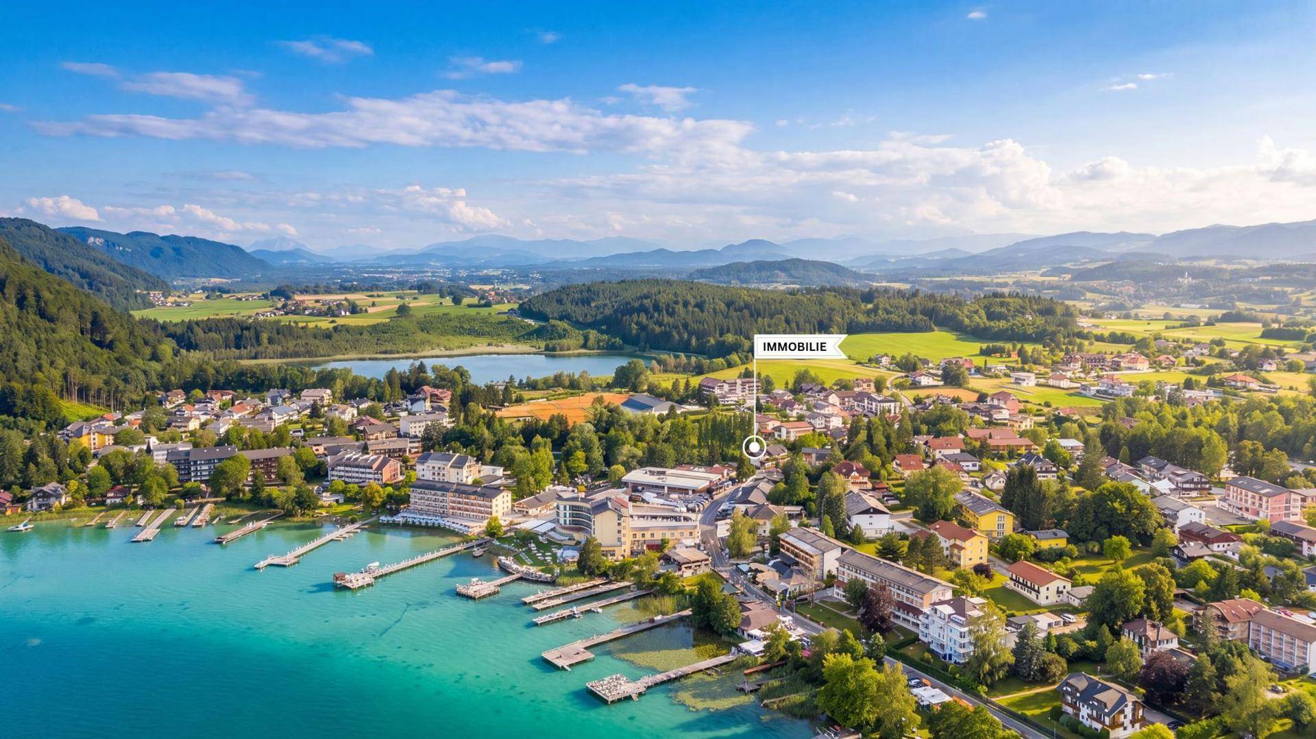 Luftaufnahme einer malerischen Stadt am See mit umliegenden Bergen und markierter Immobilie.