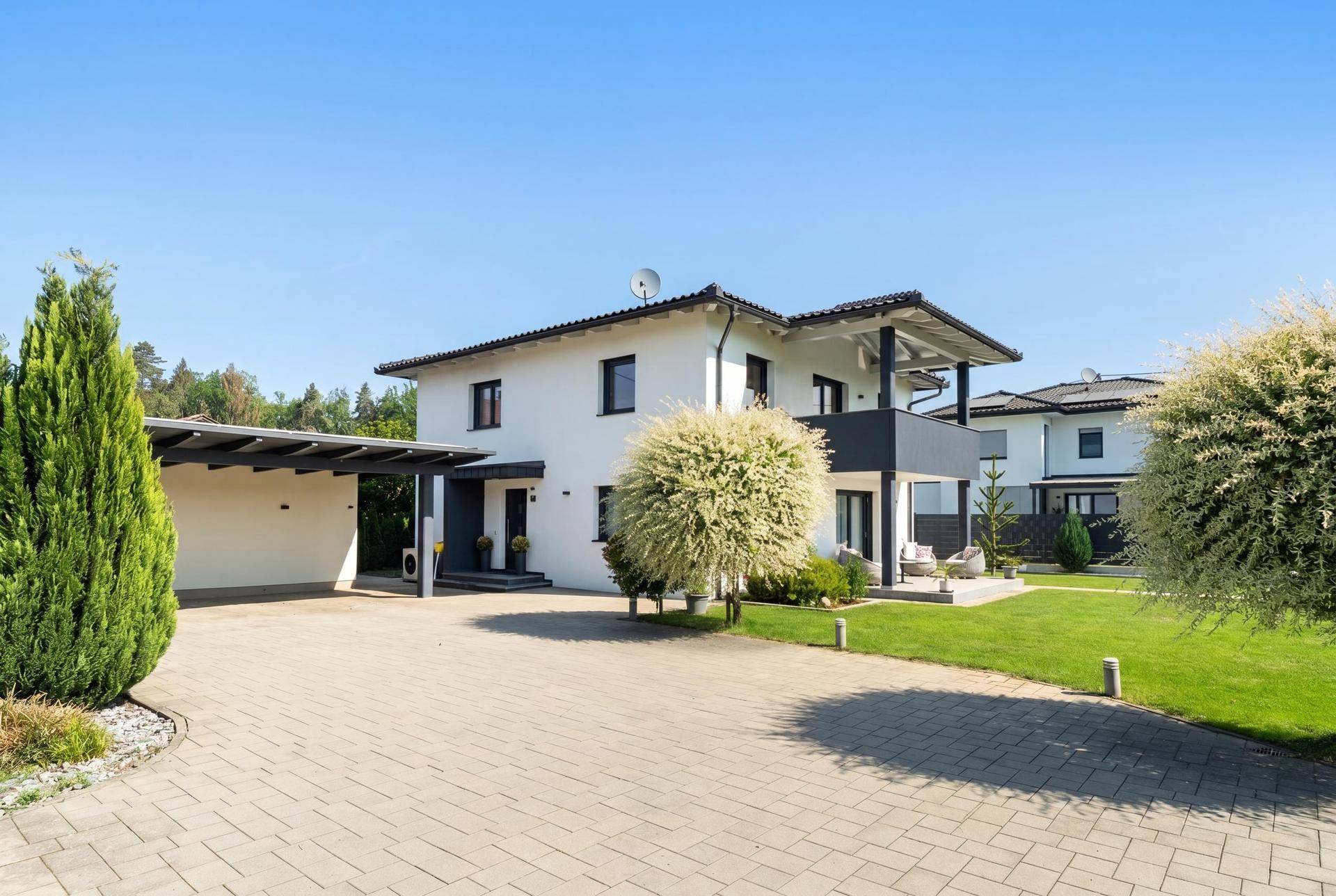 Vorderansicht des Hauses mit gepflasterter Auffahrt und überdachtem Carport.