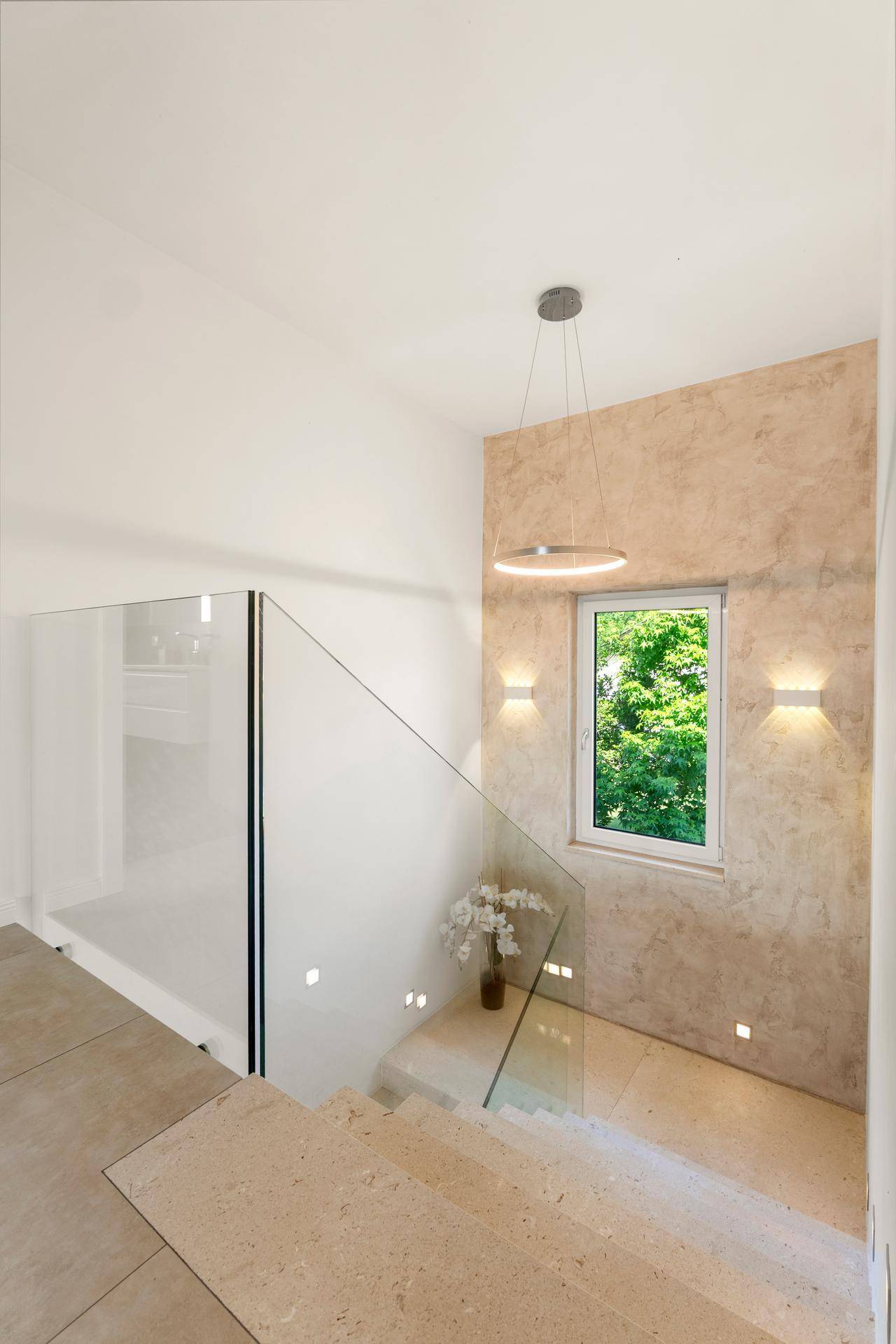 Heller Treppenabsatz mit Fenster und Blick ins Grüne, modernes Design.