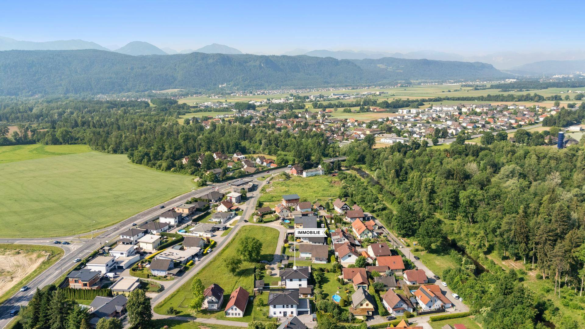 Weitläufige Luftaufnahme der Immobilie eingebettet in die grüne Landschaft.