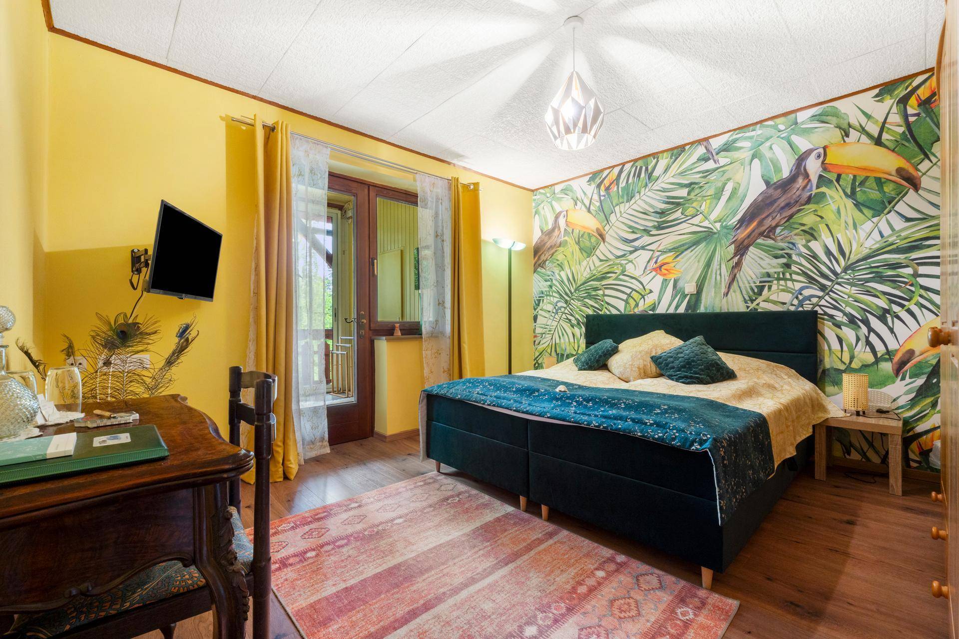 Helles Schlafzimmer mit Doppelbett, tropischer Tapete und direktem Zugang zum Balkon.