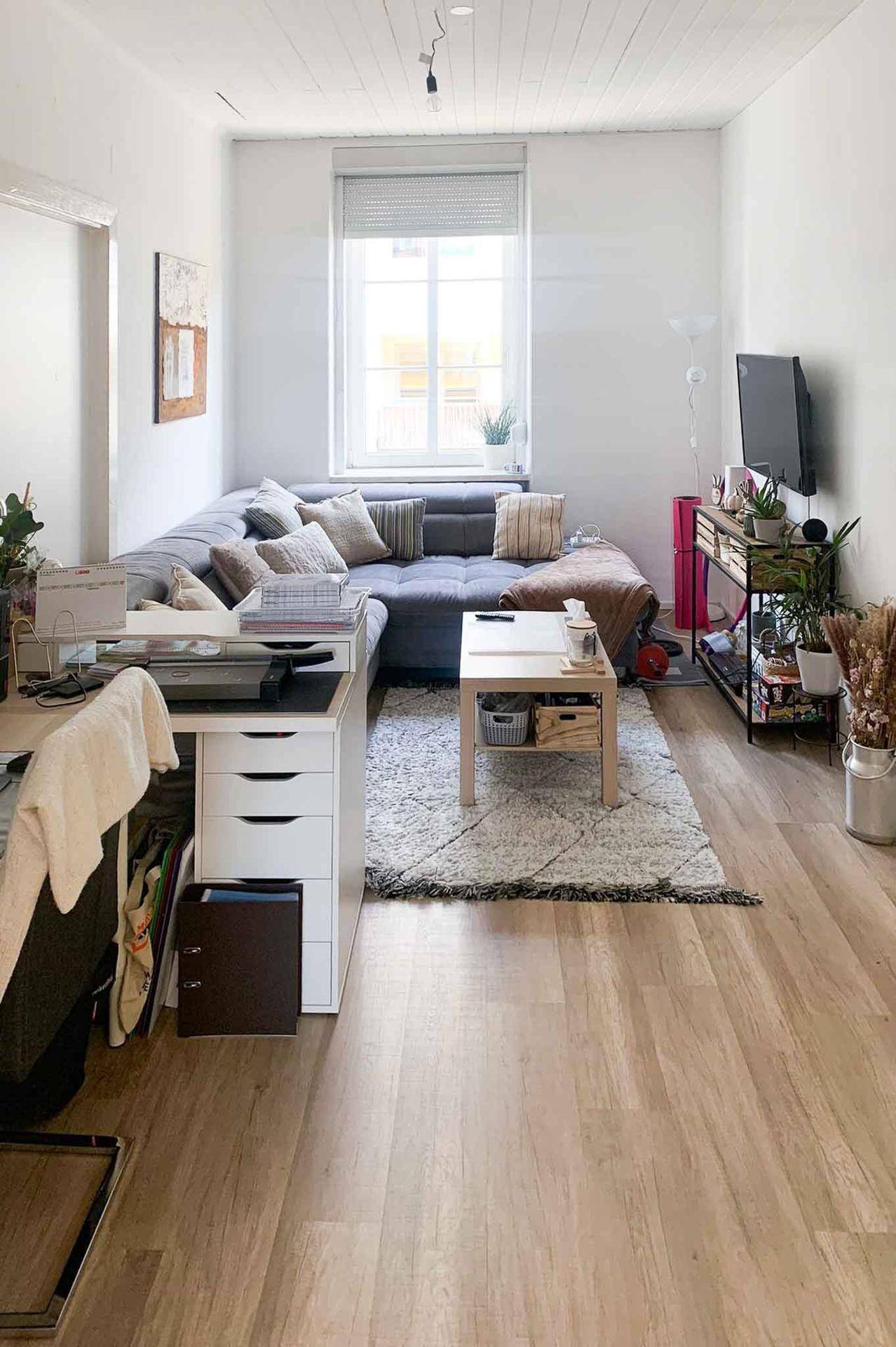 Gemütliches Wohnzimmer mit großem Ecksofa, Couchtisch und hellem Laminatboden.